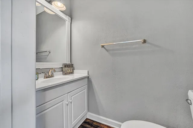 a bathroom with a granite countertop sink mirror vanity and toilet