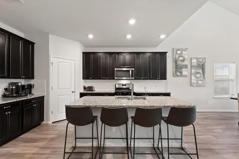 a kitchen with granite countertop a dining table chairs cabinets and stainless steel appliances