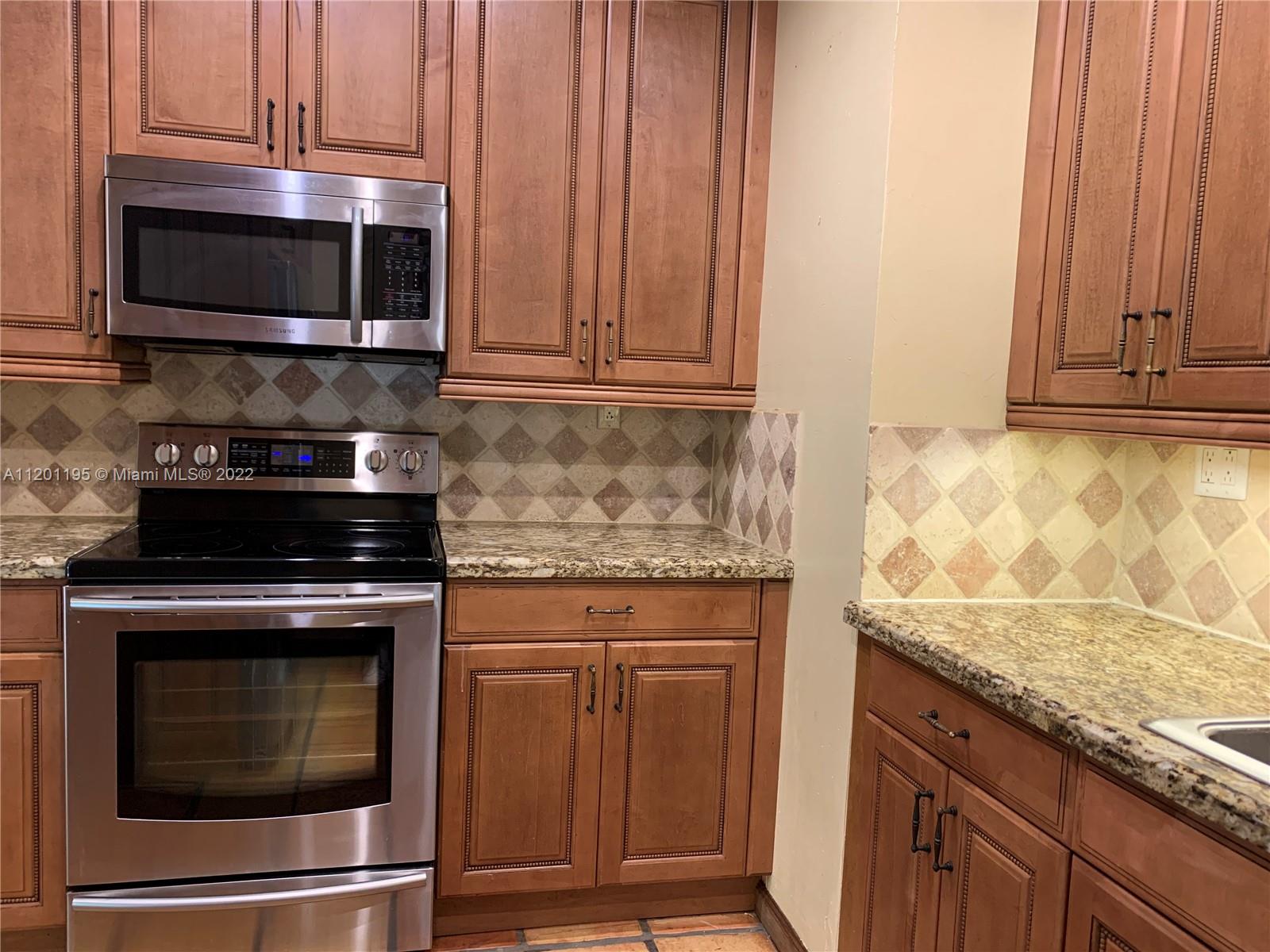 7236 School House Road Miami, FL 33143 - Photo 7 of 25 a kitchen with granite countertop cabinets stainless steel appliances and wooden cabinets