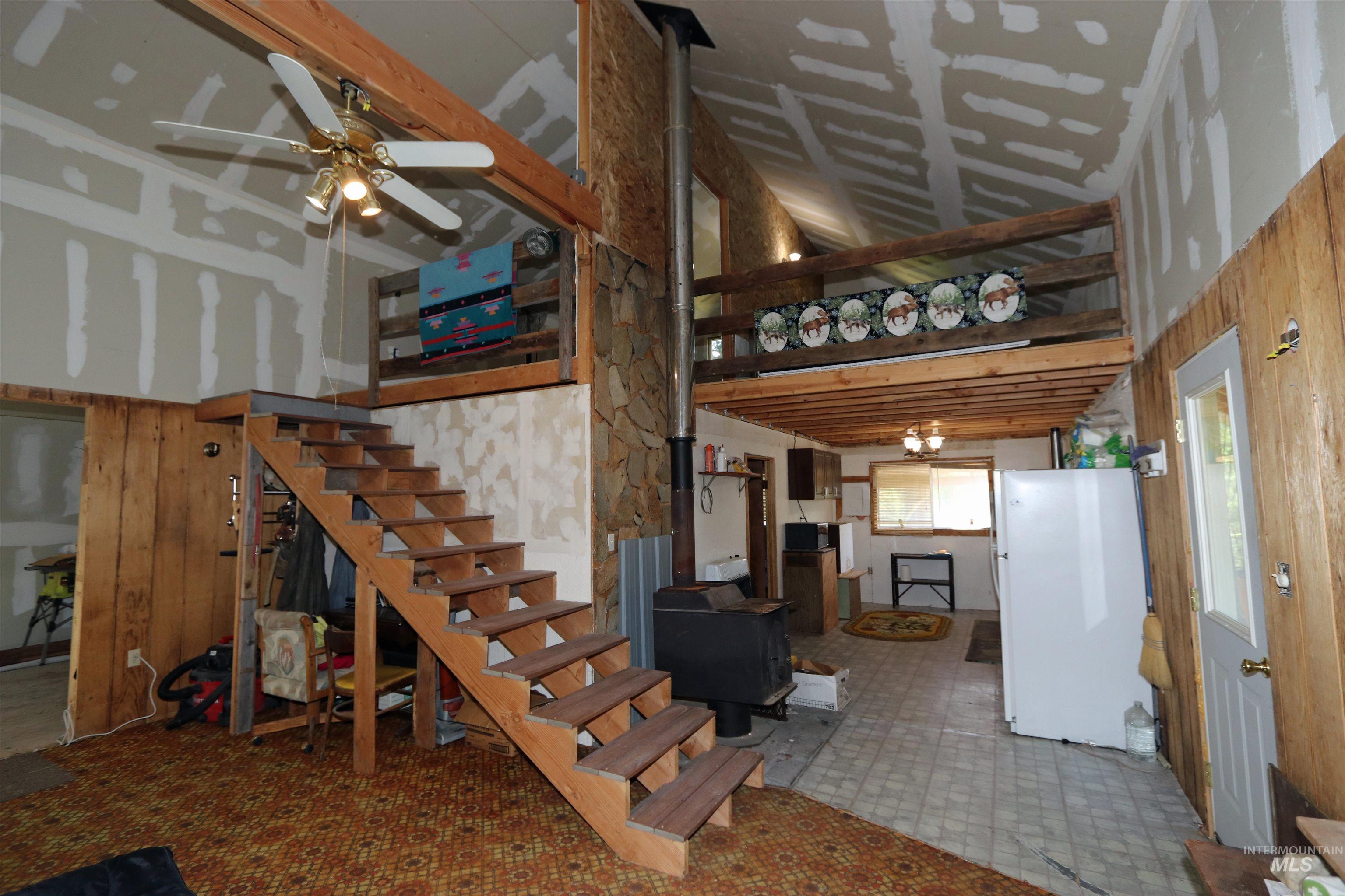 1201 Pfi Extension Elk City, ID 83525 - Photo 5 of 50 Stairs featuring high vaulted ceiling, a wood stove, tile patterned floors, ceiling fan, and wooden walls