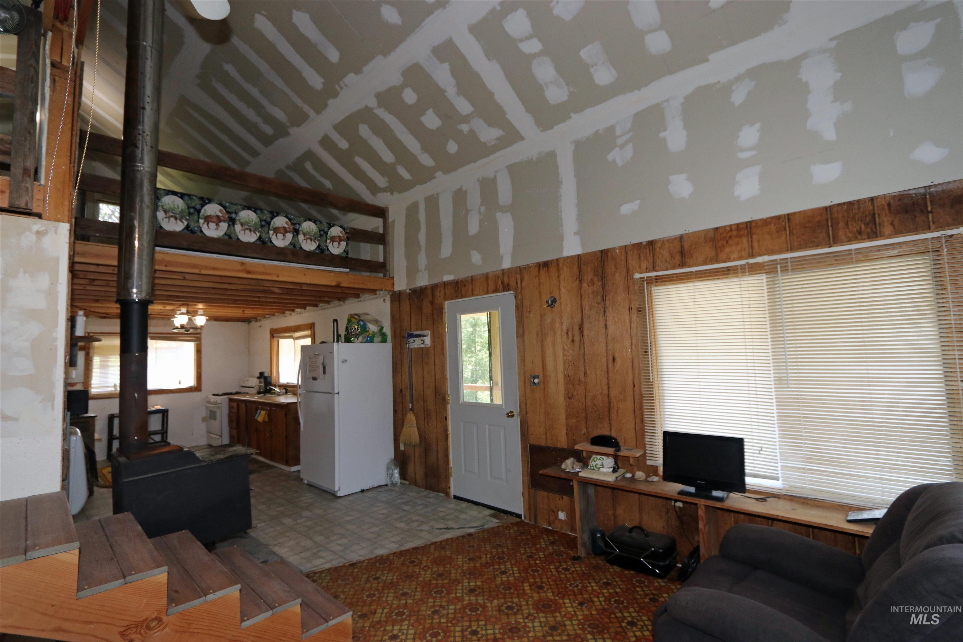 1201 Pfi Extension Elk City, ID 83525 - Photo 8 of 50 Living area featuring a towering ceiling, a wood stove, wood walls, and plenty of natural light