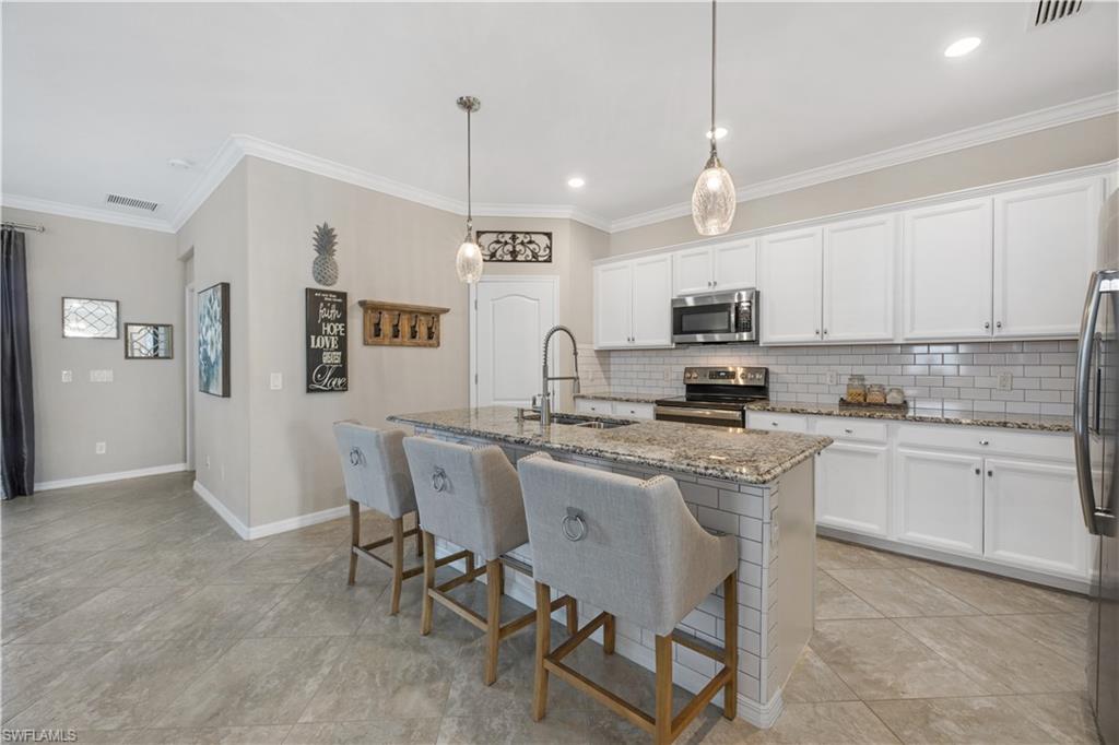 4375 Bismark Way Naples, FL 34119 - Photo 17 of 42 a kitchen with stainless steel appliances granite countertop a sink a stove a refrigerator cabinets and chairs