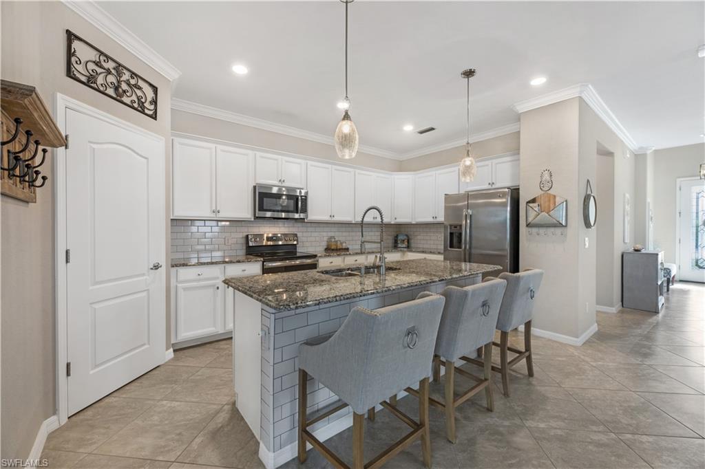 4375 Bismark Way Naples, FL 34119 - Photo 18 of 42 a kitchen with stainless steel appliances granite countertop a stove top oven a refrigerator a sink and a chairs
