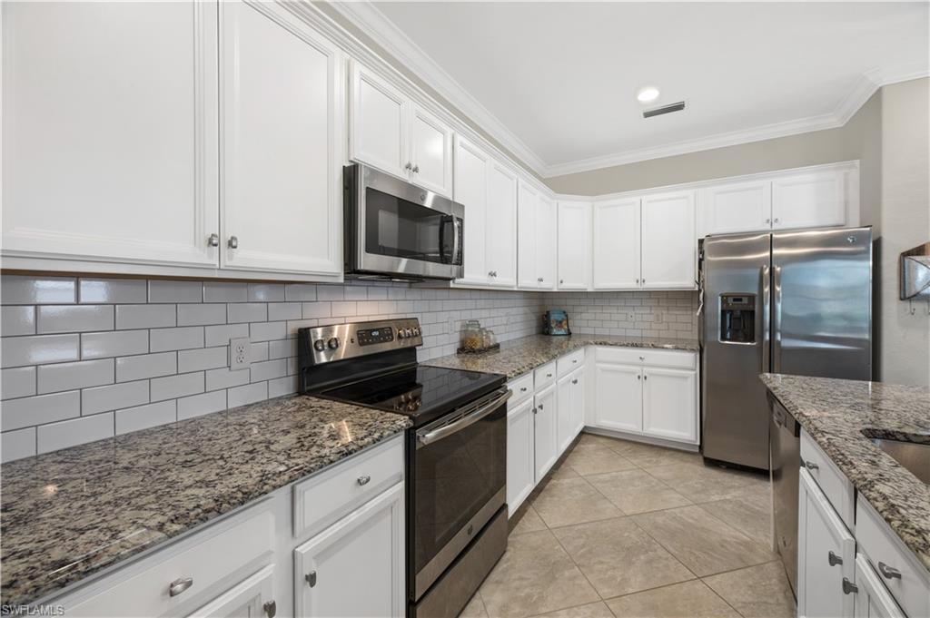 4375 Bismark Way Naples, FL 34119 - Photo 19 of 42 a kitchen with granite countertop white cabinets and stainless steel appliances