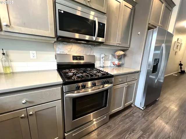 a kitchen with stainless steel appliances a stove a microwave and a sink