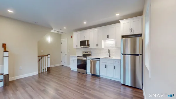 a kitchen with stainless steel appliances granite countertop a refrigerator stove and wooden floor