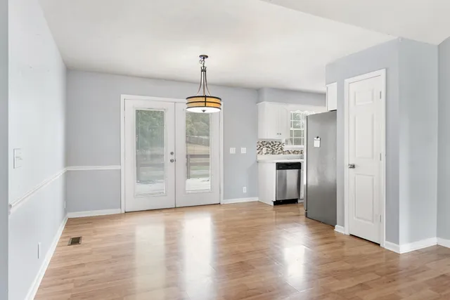 a view of a kitchen with refrigerator and wooden floor