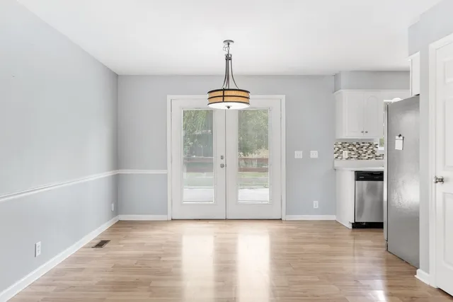 a view of an empty room with a window and kitchen view