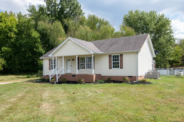 a front view of a house with a yard and trees