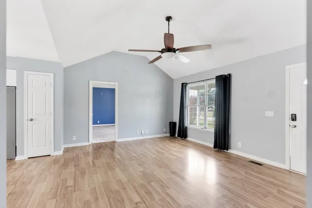 a view of an empty room with window and wooden floor