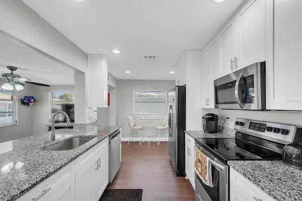 a kitchen with stainless steel appliances granite countertop a sink stove and cabinets