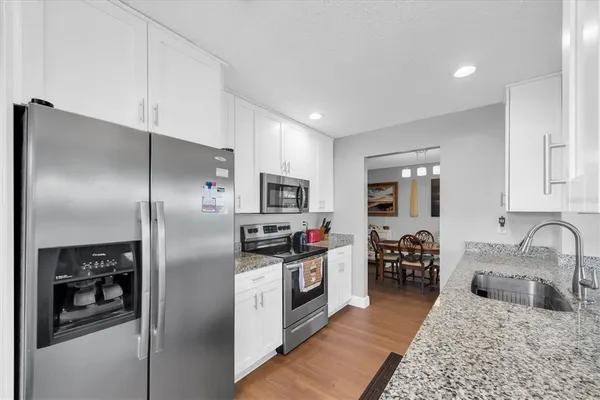 a kitchen with stainless steel appliances granite countertop a refrigerator a stove and a sink