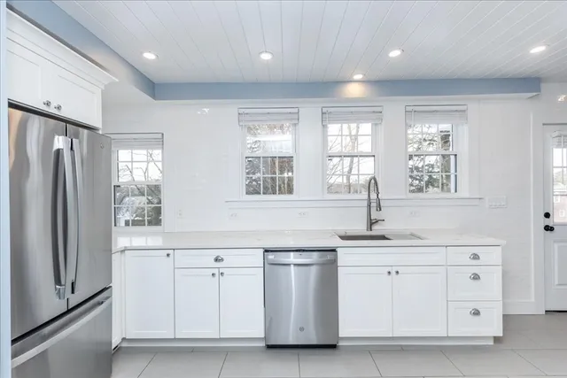 a kitchen with white cabinets and window
