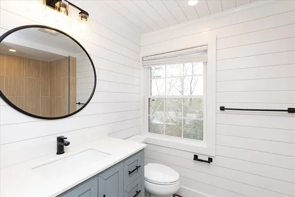 a bathroom with a sink mirror toilet and next to a window