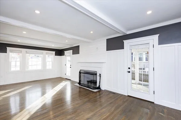 an empty room with wooden floor fireplace and windows