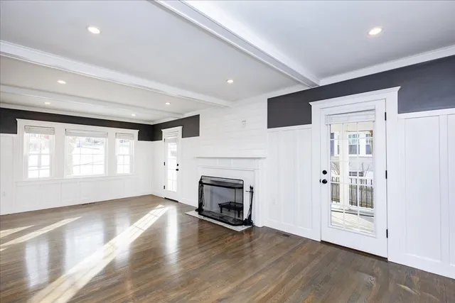 an empty room with wooden floor fireplace and windows