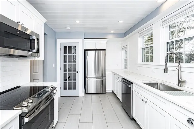 a kitchen with stainless steel appliances granite countertop a refrigerator a stove and a sink