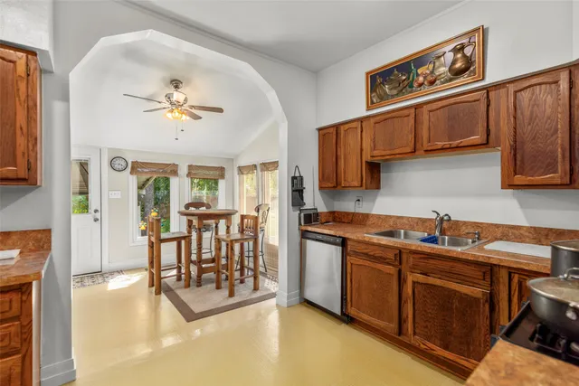 a kitchen with stainless steel appliances granite countertop a stove top oven a sink a dining table and chairs with wooden floor