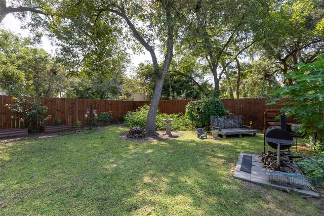 a view of a backyard with table and chairs potted plants and large tree