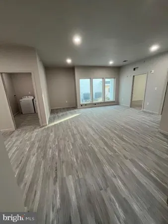 a view of empty room with wooden floor and window