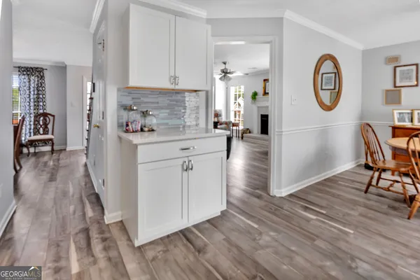 a kitchen with a refrigerator a stove top oven a clock and a view of wooden floor