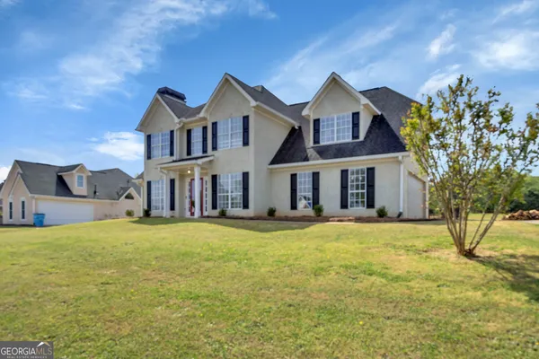 a view of a house with a yard and a large tree