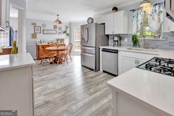 a kitchen with stainless steel appliances a refrigerator a stove a sink and white cabinets with wooden floor