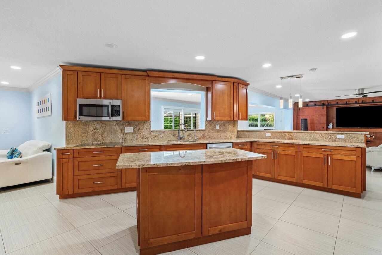 701 Buoy Road North Palm Beach, FL 33408 - Photo 18 of 52 a kitchen with kitchen island granite countertop wooden cabinets and white appliances