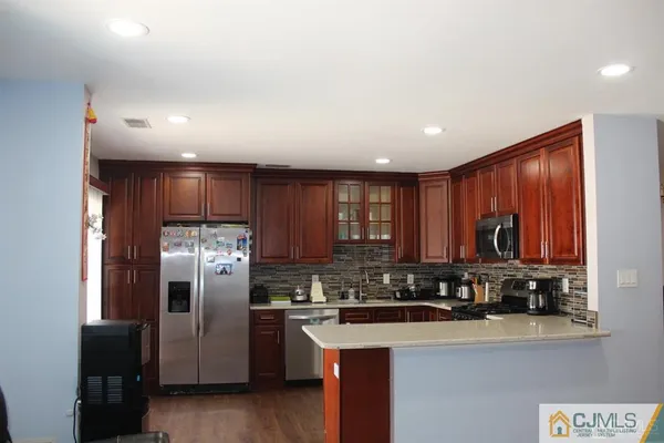 a kitchen with stainless steel appliances granite countertop a refrigerator a sink a stove a microwave and wooden cabinets