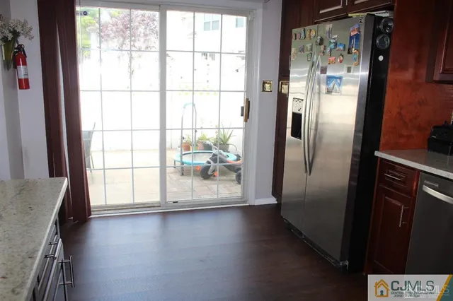 a view of a refrigerator in kitchen and an empty room