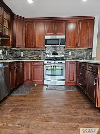 a kitchen with stainless steel appliances granite countertop wooden cabinets a stove top oven a sink and dishwasher