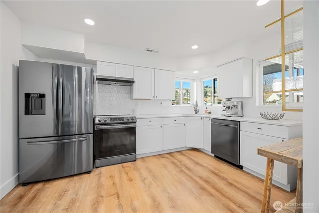 a kitchen with a refrigerator wooden floor and white cabinets