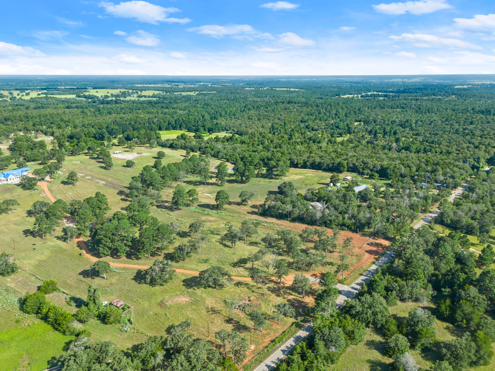 170 Split Oak Road Smithville, TX 78957 - Photo 28 of 31 Rolling green landscape unfolds under an expansive sky, featuring mature trees and a tranquil rural setting.