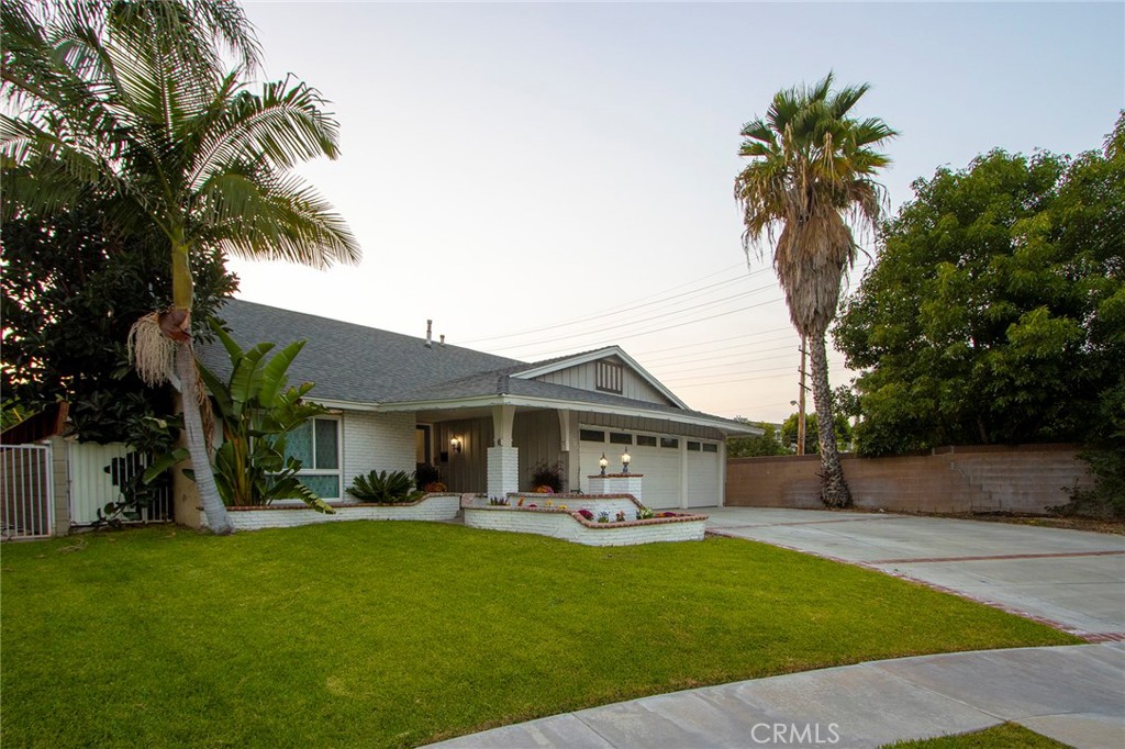 a front view of a house with a garden and palm trees