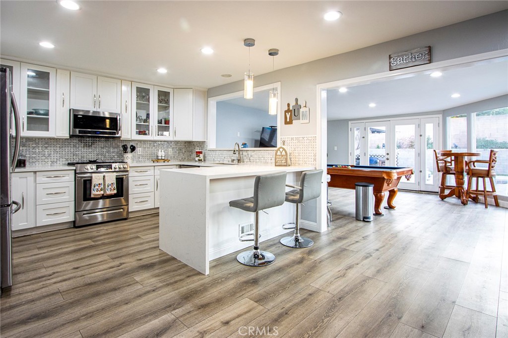 11503 Tropico Avenue Whittier, CA 90604 - Photo 3 of 5 a kitchen with stainless steel appliances granite countertop a stove top oven a sink dishwasher a dining table and chairs with wooden floor