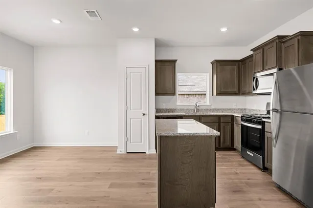 a kitchen with stainless steel appliances granite countertop a refrigerator a sink and a stove