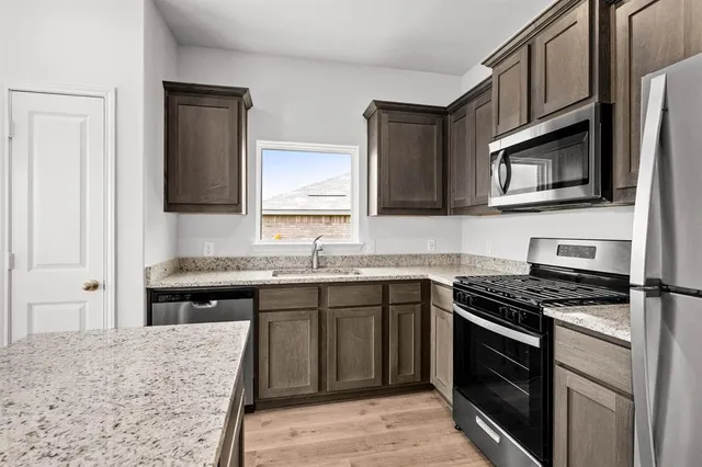 a kitchen with stainless steel appliances granite countertop a stove microwave and sink