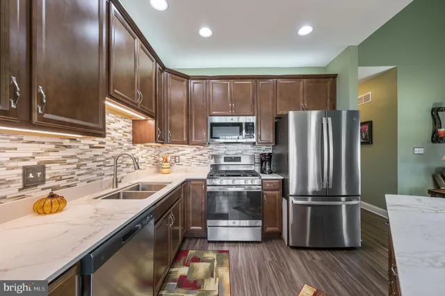 a kitchen with stainless steel appliances granite countertop a sink a stove and a refrigerator