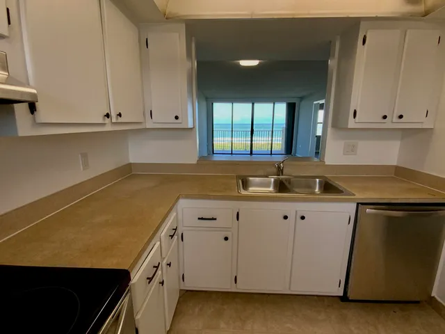a kitchen with granite countertop white cabinets and a sink