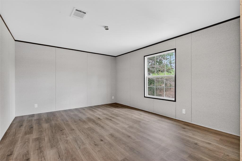 419 Lily Trail Interlachen, FL 32148 - Photo 23 of 82 a view of an empty room with wooden floor and a window