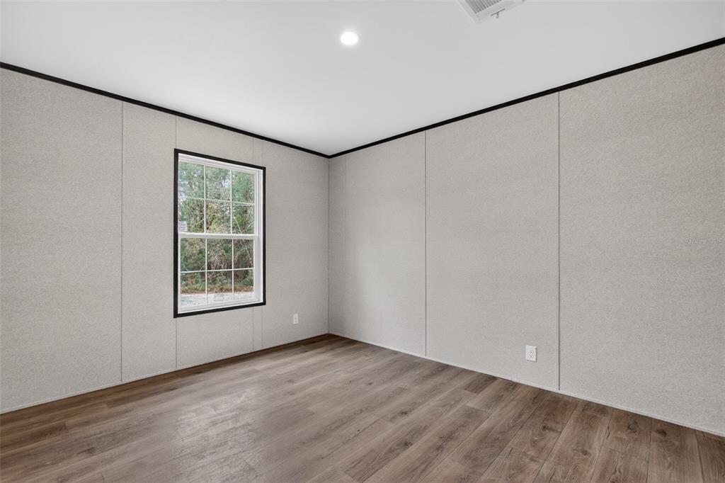 419 Lily Trail Interlachen, FL 32148 - Photo 29 of 78 an empty room with wooden floor and windows