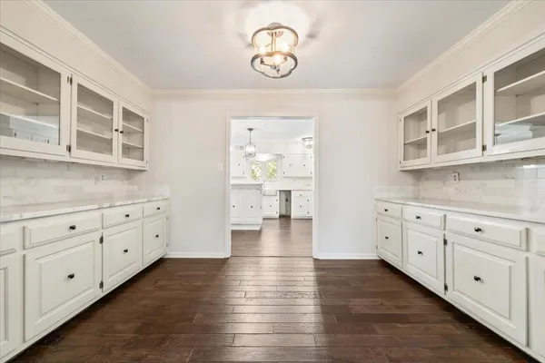 a hallway with white cabinets and wooden floors