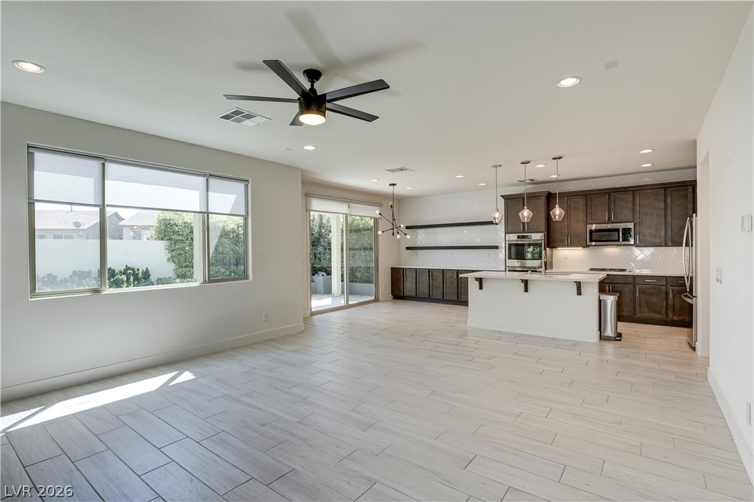 5954 Smith Valley Road Las Vegas, NV 89148 - Photo 10 of 23 A well-lit, open-concept living area seamlessly transitions to a modern kitchen with sleek finishes and outdoor access.