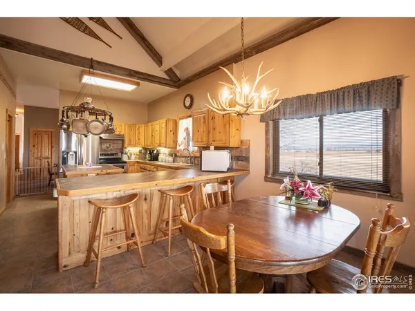 a dining hall with stainless steel appliances kitchen island granite countertop a dining table chairs and a large window