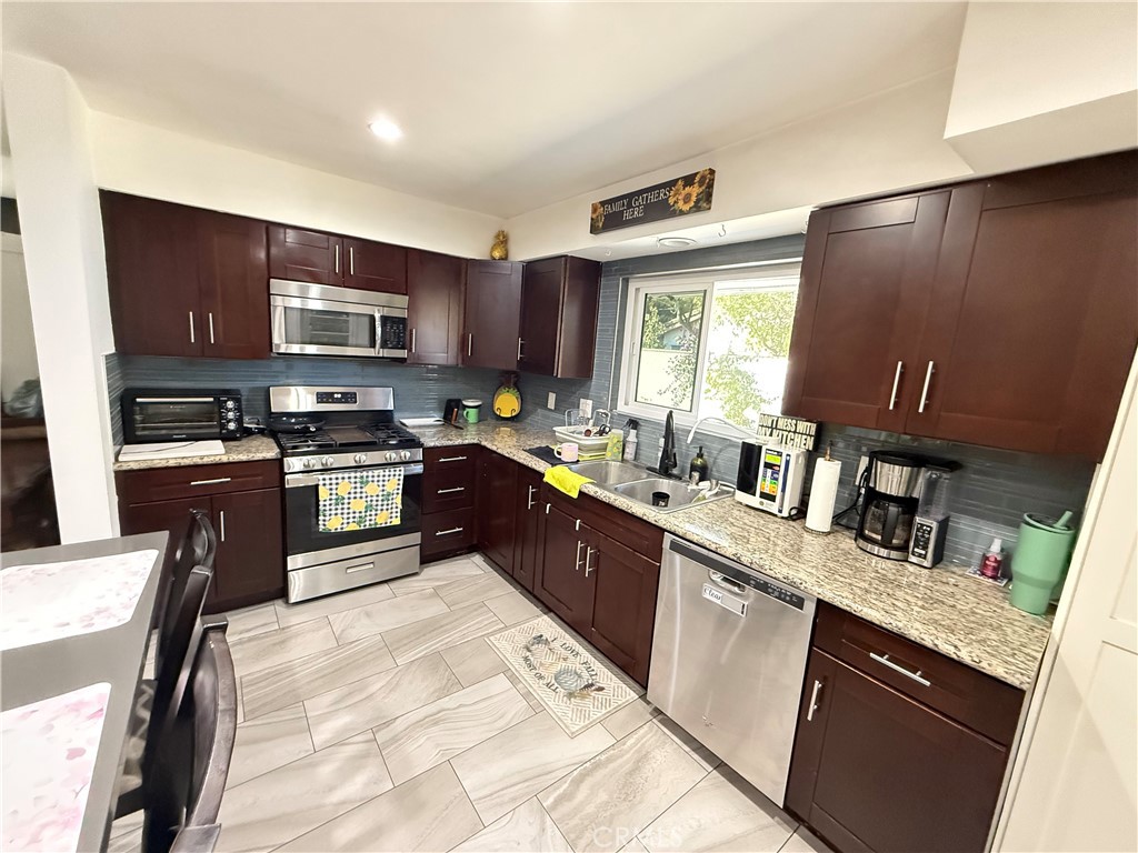 5836 Old Ranch Road Riverside, CA 92504 - Photo 46 of 59 a open kitchen with stainless steel appliances granite countertop a stove top oven a sink dishwasher a dining table and chairs with wooden floor