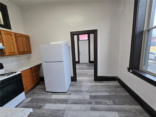 a view of a refrigerator in kitchen and an empty room