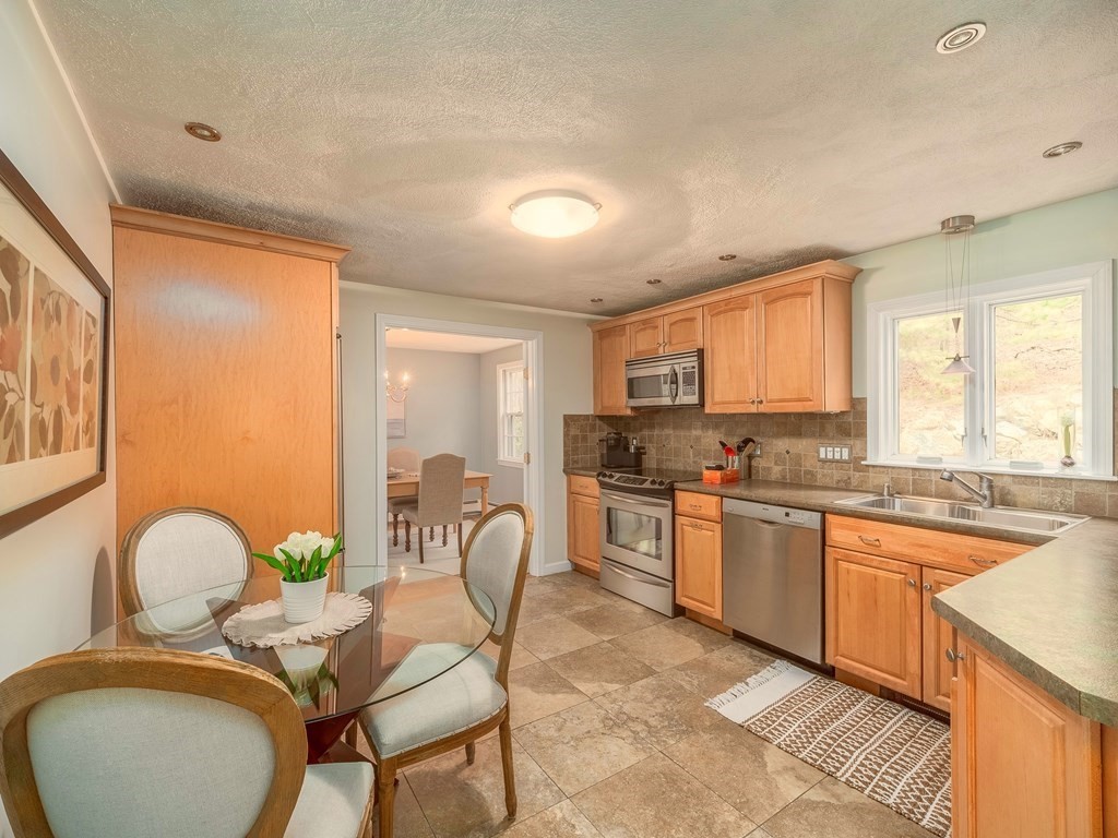 59 Rattlesnake Hill Road Andover, MA 01810 - Photo 11 of 39 a large kitchen with stainless steel appliances granite countertop a stove a sink dishwasher a dining table and chairs with wooden floor