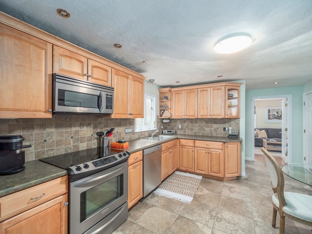 59 Rattlesnake Hill Road Andover, MA 01810 - Photo 12 of 39 a kitchen with stainless steel appliances granite countertop a stove top oven a sink dishwasher a dining table and chairs with wooden floor
