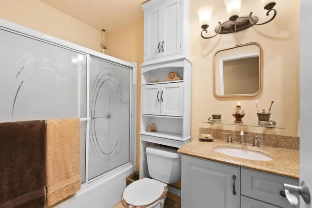 a bathroom with a granite countertop sink vanity mirror bathtub shower and a toilet