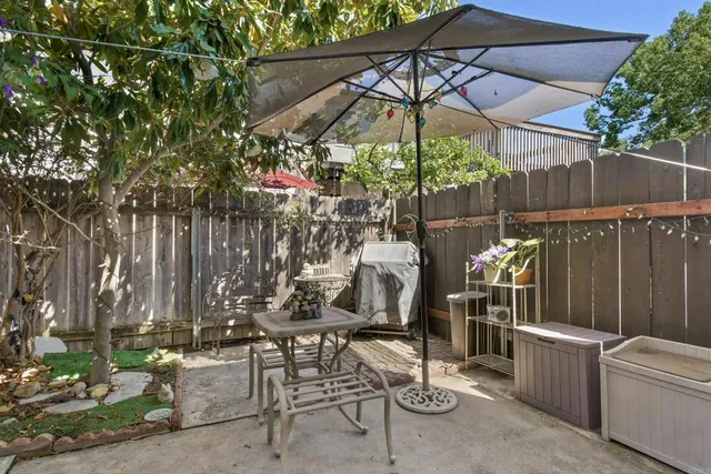 a view of a patio with table and chairs under an umbrella